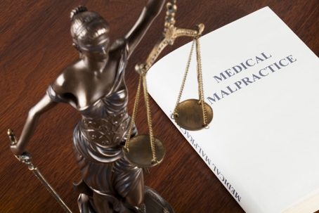 Law book on medical malpractice next to Lady Justice.